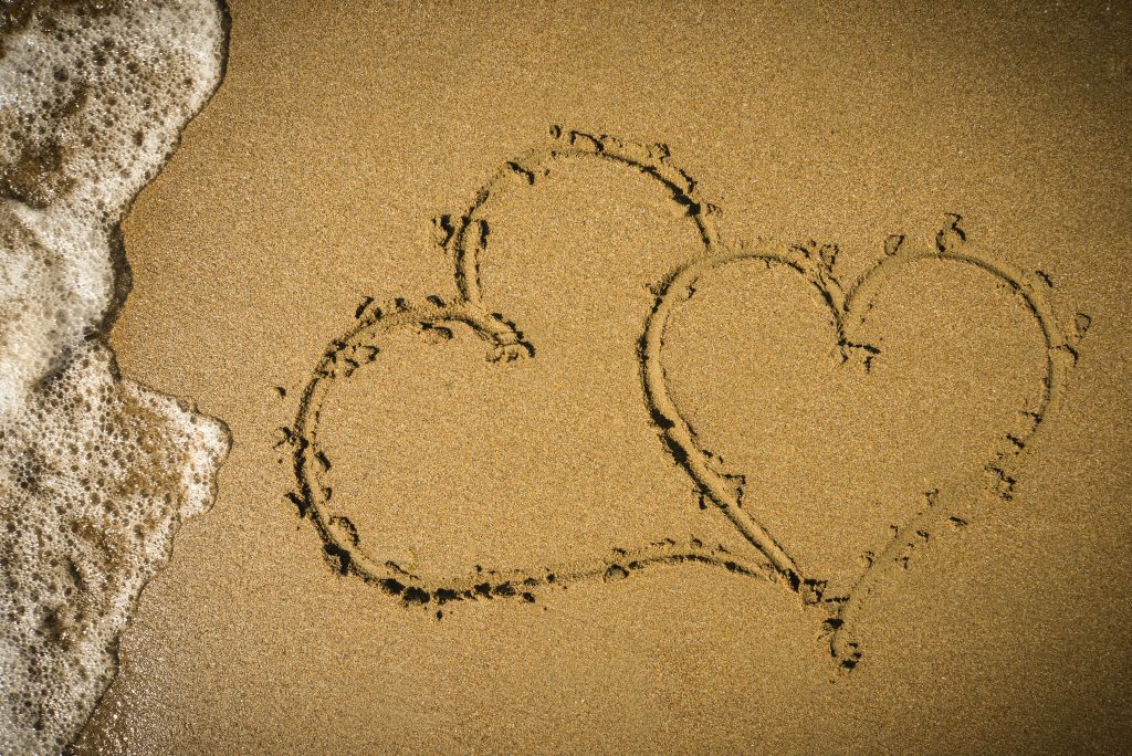 two hearts drawn in the beach sand